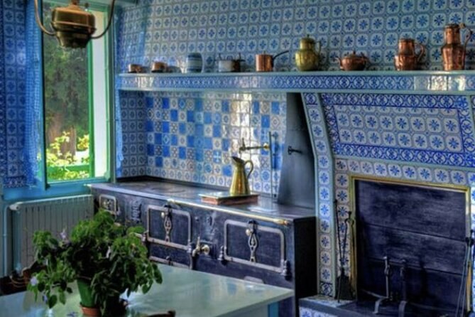 A kitchen lined with blue and white tiles, copper pans above the range