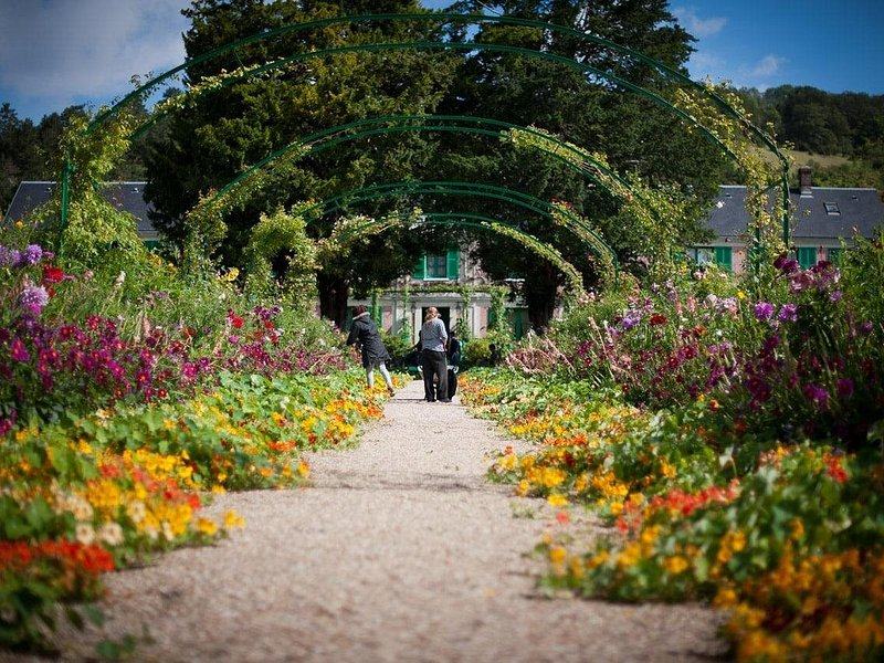 The central garden path under a run of iron arches, flower beds on both sides