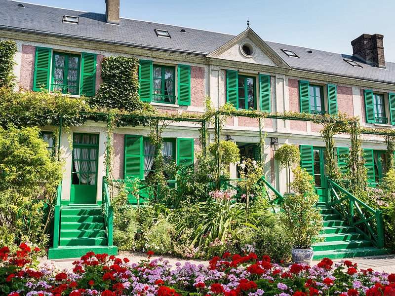 Green steps and shutters on the front of the house, climbing plants over the walls