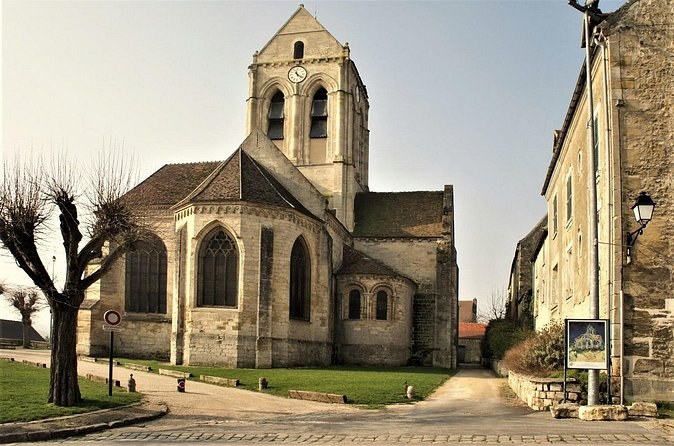 The church at Auvers-sur-Oise beside a board showing Van Gogh's painting of it