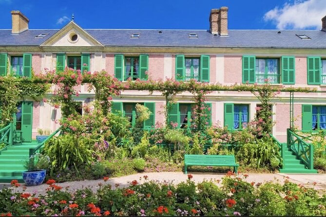 The long pink house with green shutters behind beds of tulips